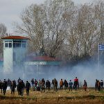 Migrants stand near a cloud of tear gas as they gather on the Turkish-Greek border near Turkey’s Pazarkule border crossing with Greece’s Kastanies