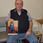 Peter Stathopoulos holds a photo from his military days.