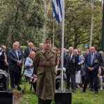 Giorgos Kypros stands alert beside the Greek flag.