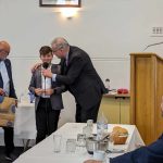 Nikos Kydas offers the ouzo to Stelios Kakavelakis as his dad looks on while Hellenic RSL President Emanuel Karvelas suggests they wait he turns 18 before drinking it.