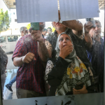 Lining up on Wednesday to check a list of names of people who were going to be allowed to cross the border into Egypt from Rafah, Gaza, on Thursday.Credit…Samar Abu Elouf for The New York Times