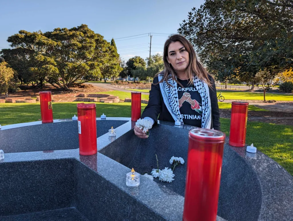 Lidia Thorpe drops a white carnation into the monument to honour victims of Genocide.