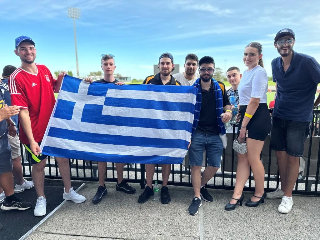 Young fans waving the Greek flag at The Greek Herald Cup in 2024 — capturing the pride and passion that continue to unite generations of supporters.