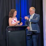 GCM Member Simela Stamatopoulos takes the stage with GCM Vice President Marinis Pirpiris