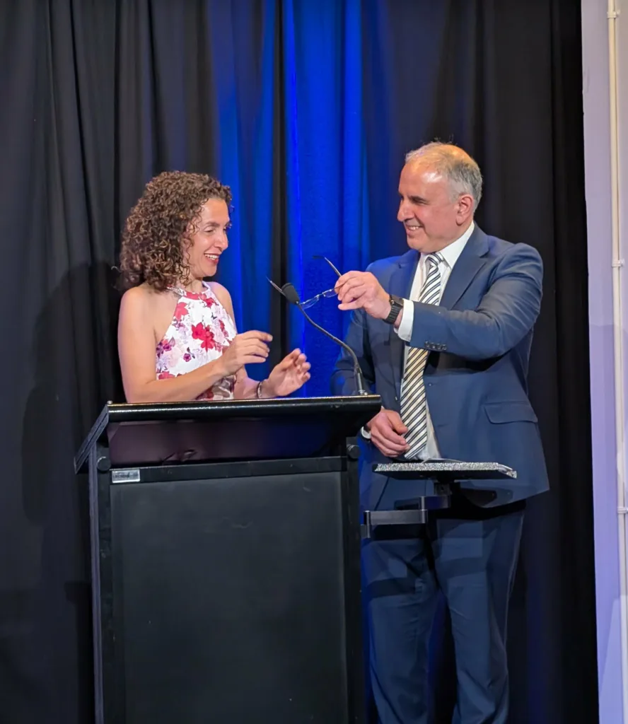 GCM Member Simela Stamatopoulos takes the stage with GCM Vice President Marinis Pirpiris